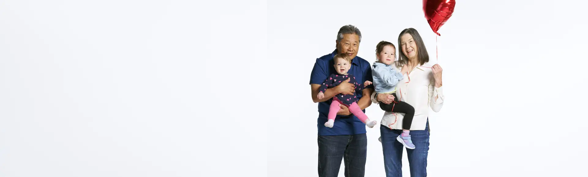 Donna and Barry holding their two small children and a red heart-shaped balloon