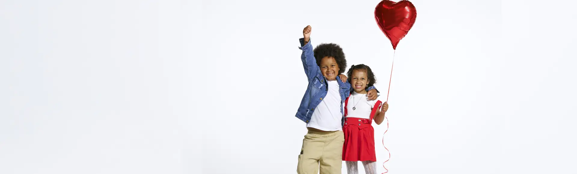 Nora and her sister smiling and holding a red heart balloon